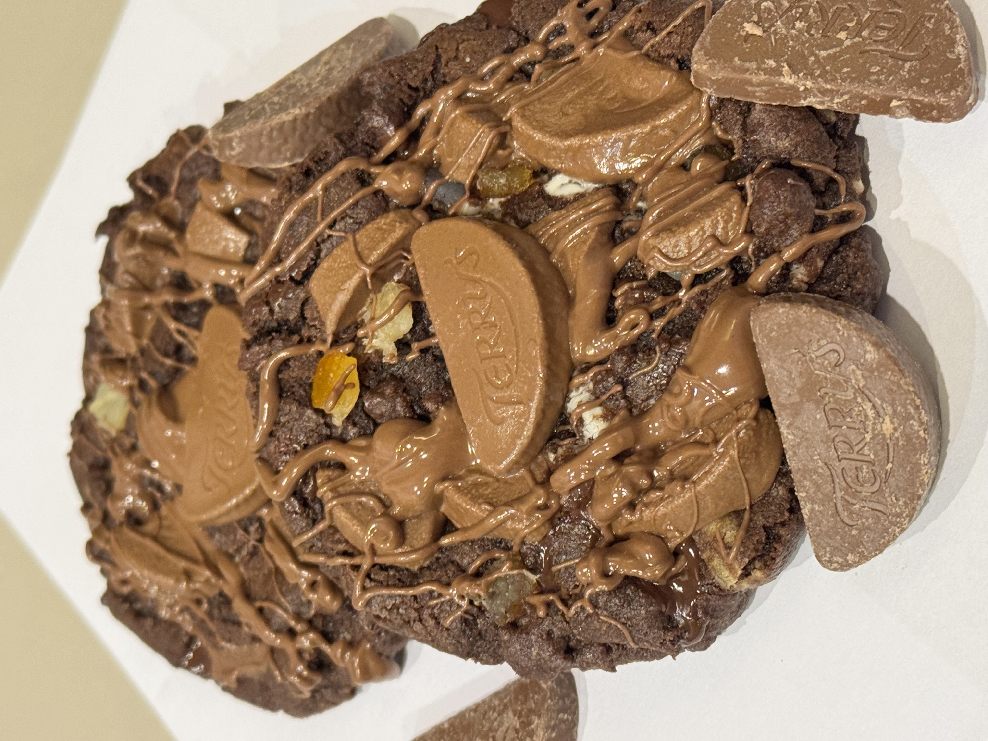 A thick chocolate cookie topped with several Terry’s Chocolate Orange segments and drizzled with melted milk chocolate.